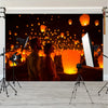A banner featuring a dark background with numerous glowing orange lanterns and two people looking towards the lights.