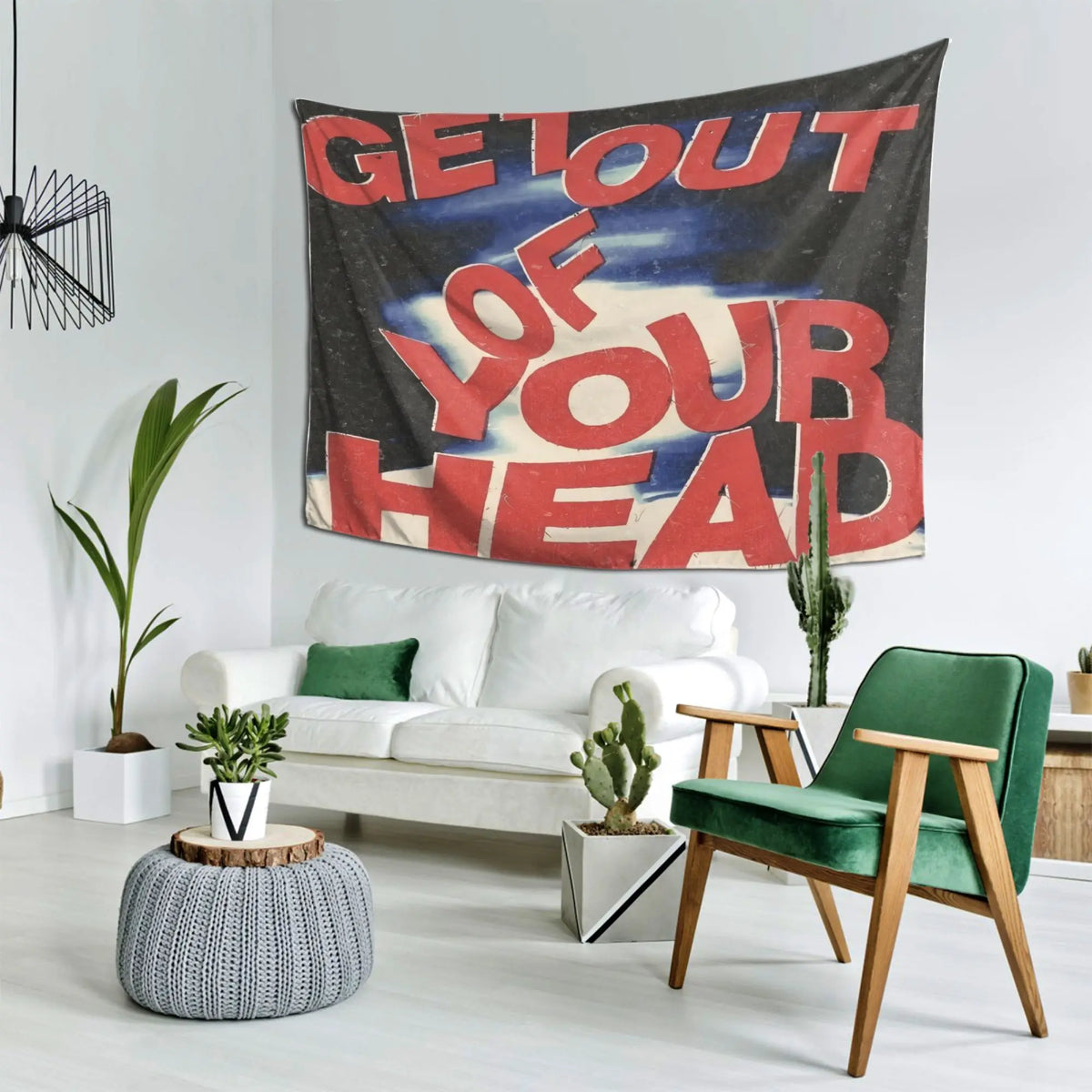 A large red and black tapestry with white text that reads Get Out of Your Head hanging on a white wall.