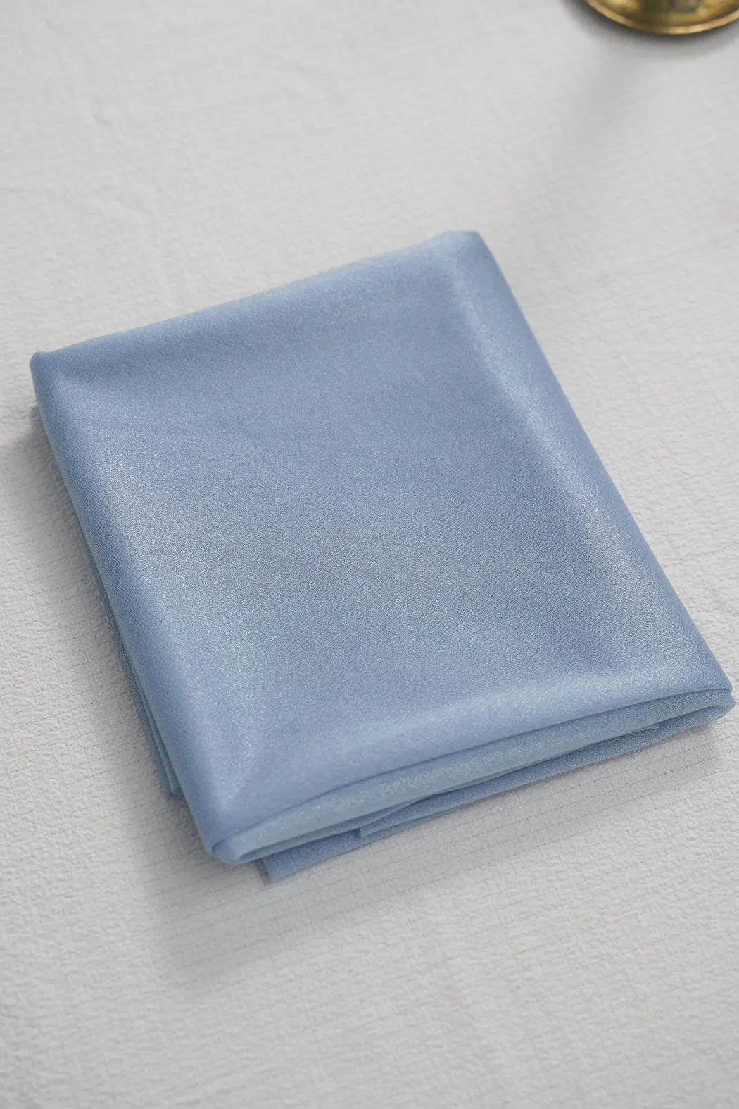 A folded piece of light blue chiffon fabric used for wedding arch drape.