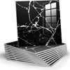 A black marble peel-and-stick wall panel with white veining is displayed on a stack of similar panels.