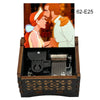 A hand-cranked wooden music box featuring an illustration of a man and woman in profile.