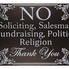 A black metal door sign with white text listing prohibited activities such as soliciting, salesman, fundraising, politics, an