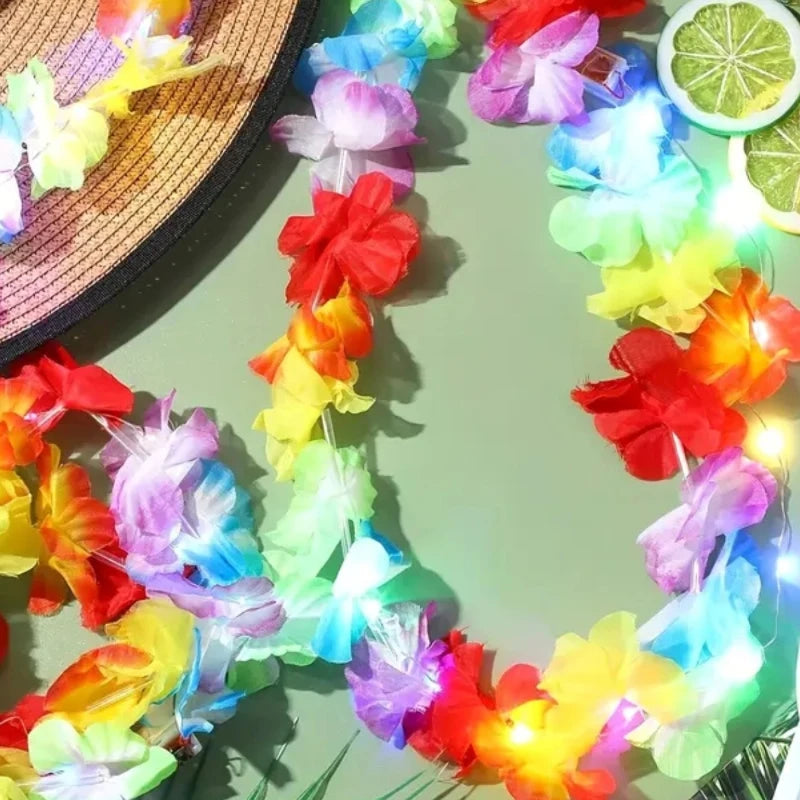 A colorful glow-in-the-dark LED Hawaiian lei necklace with tropical flowers is displayed against a green background.