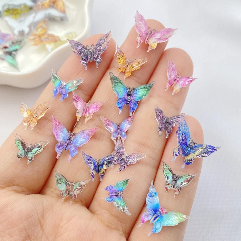 A hand holds a collection of colorful resin butterfly embellishments in various shades of purple, blue, and pink.