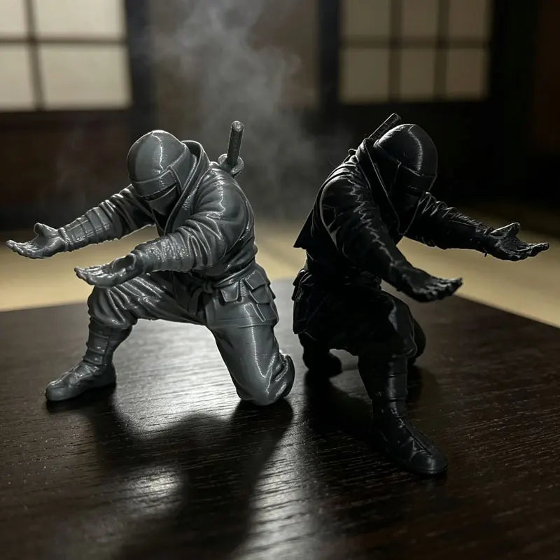 Two dark ninja figures in gray and black are shown standing on a wooden desk with smoke effects.