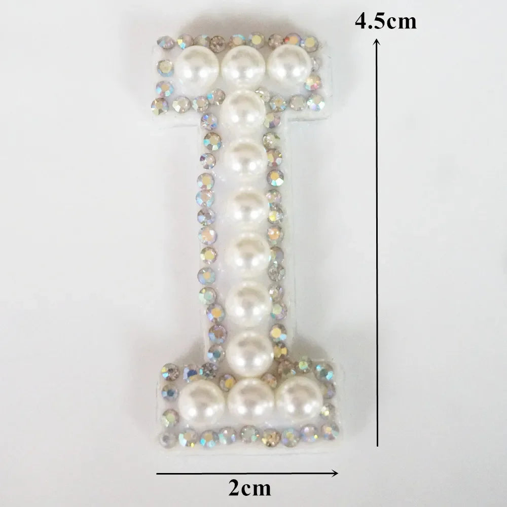 A rhinestone patch shaped like the letter T, featuring pearl and clear stones, measuring 4.5cm high and 2cm wide.