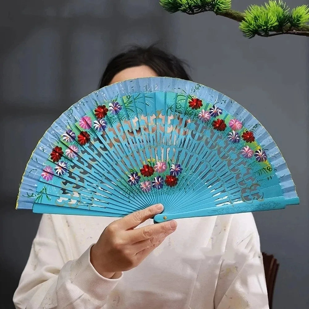 A hand-painted decorative folding fan with blue and pink floral designs is held open.