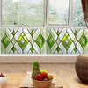 A close-up view of retro European green leaf privacy window film displayed in a window frame.