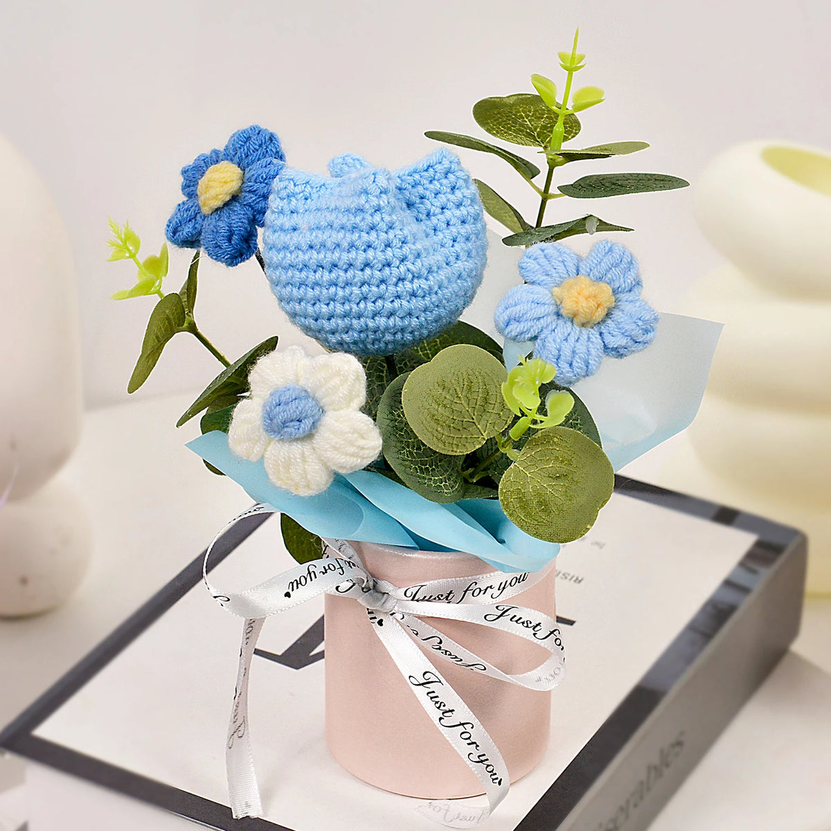 A handmade crochet tulip bouquet featuring blue and white flowers in a pink pot