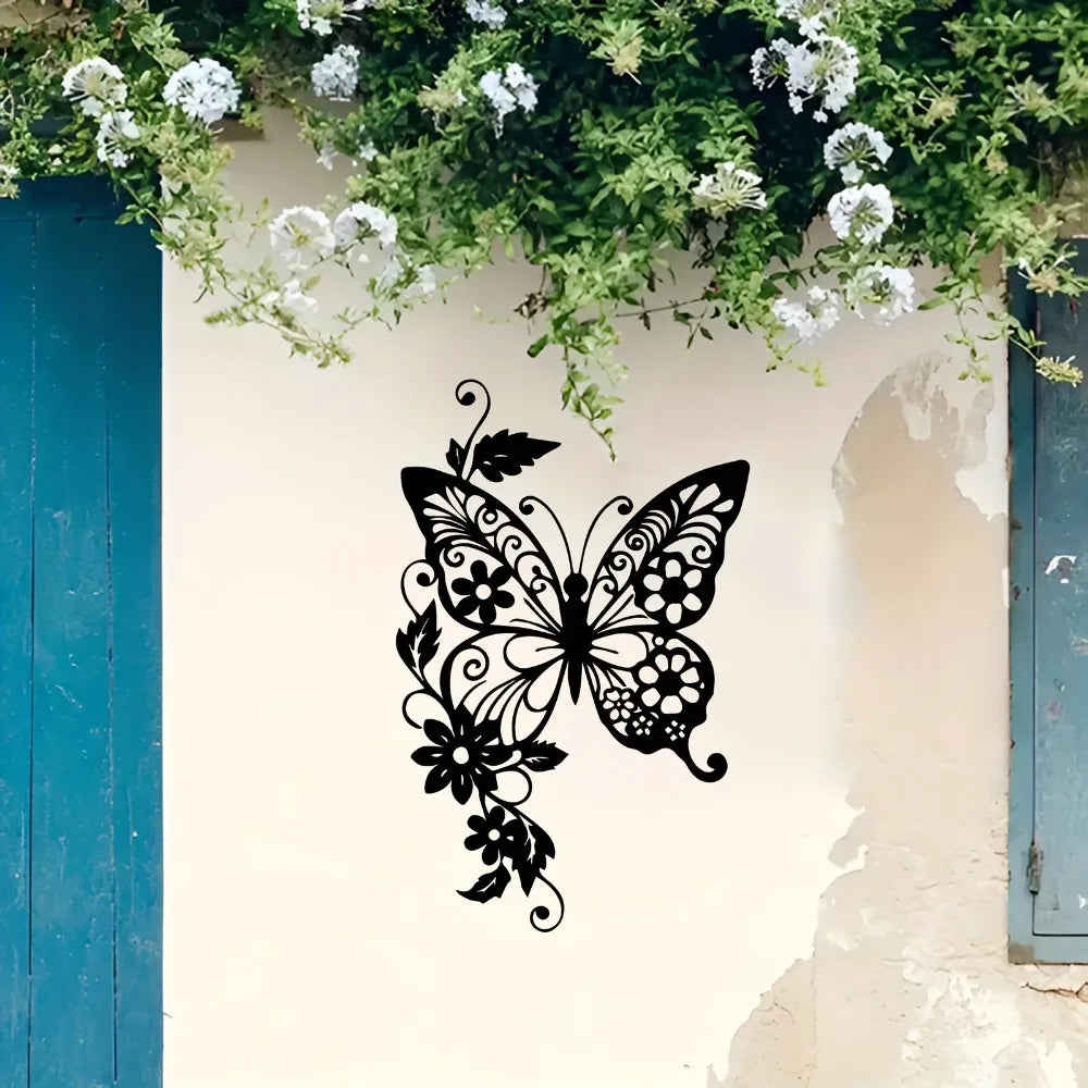 Black silhouette of an Art Nouveau butterfly and floral design on a white wall decorated with green vines.