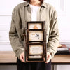 A person holds a dark wooden rotating photo frame with twelve display slots.