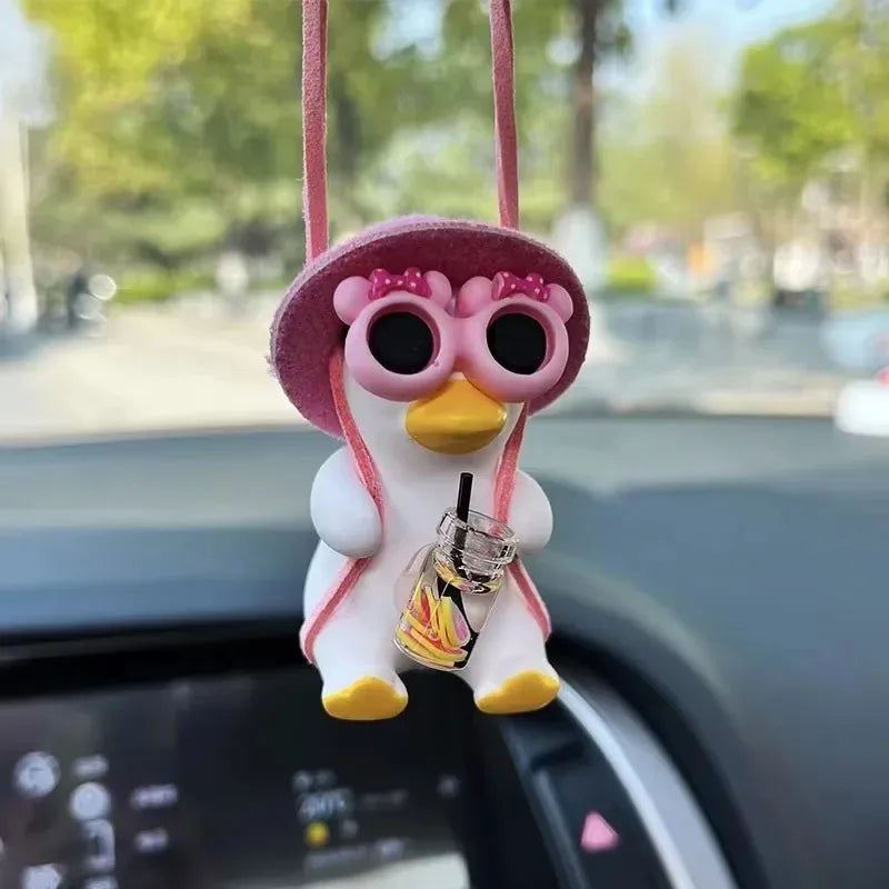 A cute pink anime duck ornament with large eyes and a yellow beak hanging from a string.