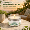 A jar of Citronella scented candle sitting on a stone surface with greenery in the background.