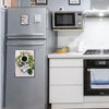A silver refrigerator and a white kitchen counter display magnetic picture frames on the wall.