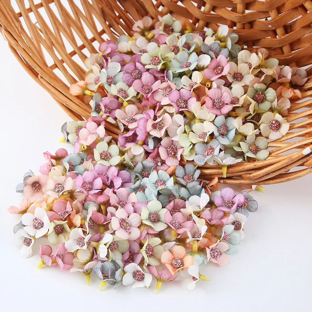 A pile of silk artificial flower heads in soft pink, peach, and pale blue colors resting in a woven basket.