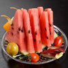 Sliced watermelon served on a clear acrylic plate with garnishes.