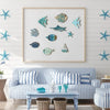 A display of ten wooden hanging fish wall decorations in various shades of blue and teal against a white wooden panel.