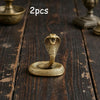 Two brass snake sculptures with intricate texture displayed on a dark wooden surface.