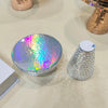 A round, iridescent disco ball decoration with a mushroom shape is displayed on a light surface.