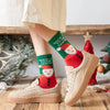 A pair of tan canvas shoes paired with green Christmas socks featuring Santa and reindeer patterns.