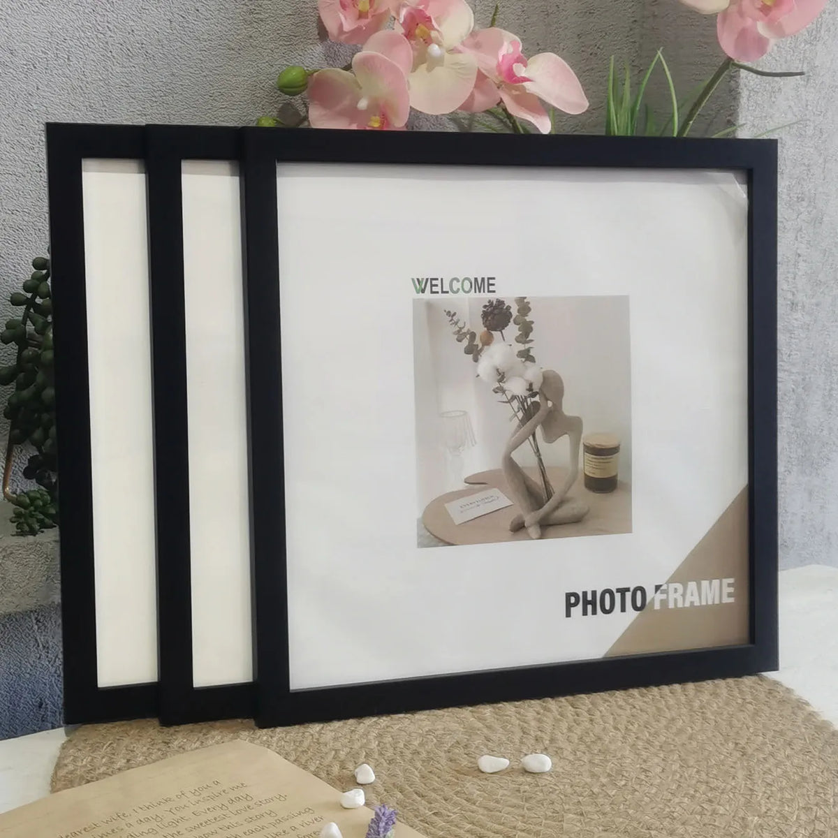 A set of three black photo frames with white mats displayed on a beige surface.