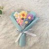 A bouquet of handcrafted crochet sunflowers in pastel colors, including yellow, pink, and purple flowers, wrapped in light bl