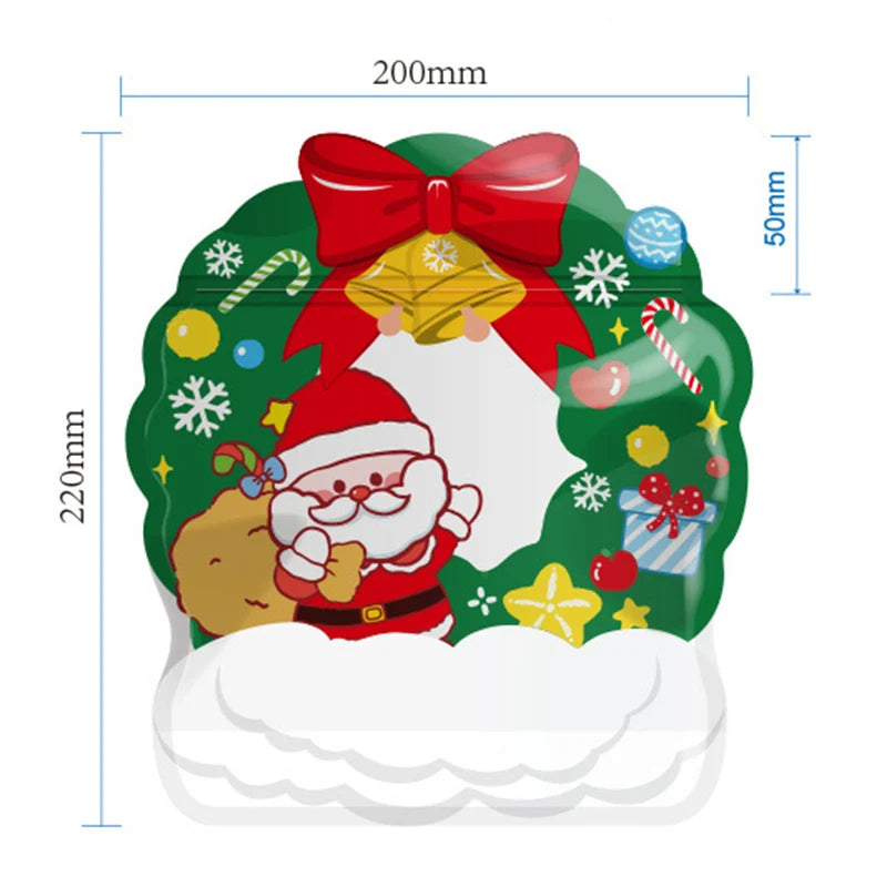A green reusable Christmas gift bag decorated with red bow, gold bells, snowflakes, and a Santa hat.