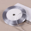 Silver satin ribbon spool with a thin ribbon unwound on a white background