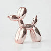 A pink resin balloon dog sculpture with a whimsical design, used as home or office decor.