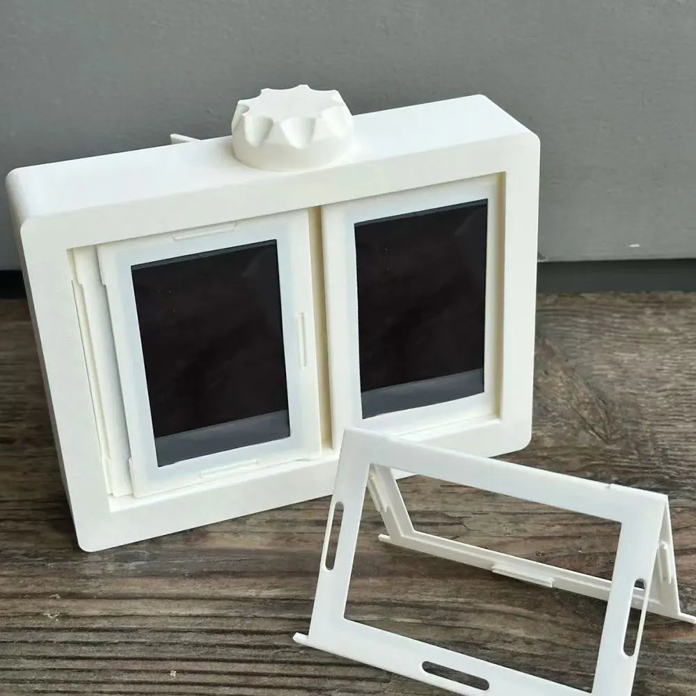 A white rotating flip photocard display frame with a decorative top, shown on a wooden surface.