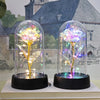 Rose de verre éternelle avec une lumière LED, exposée dans un contenant en verre transparent sur une base noire.