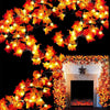 An autumn leaf garland with bright orange LED lights decorating a fireplace mantel and surrounding foliage.
