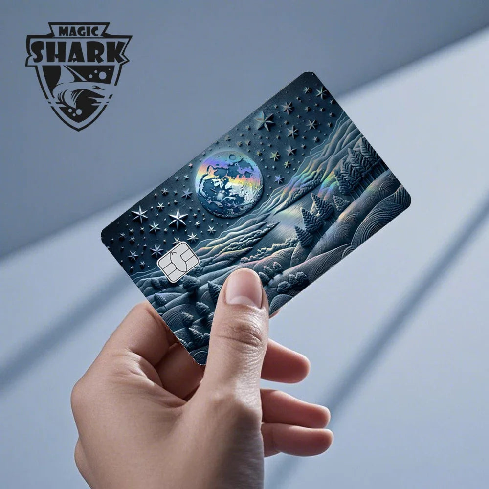 A hand holds a holographic cat credit card skin sticker featuring a cosmic scene and mountain landscape.