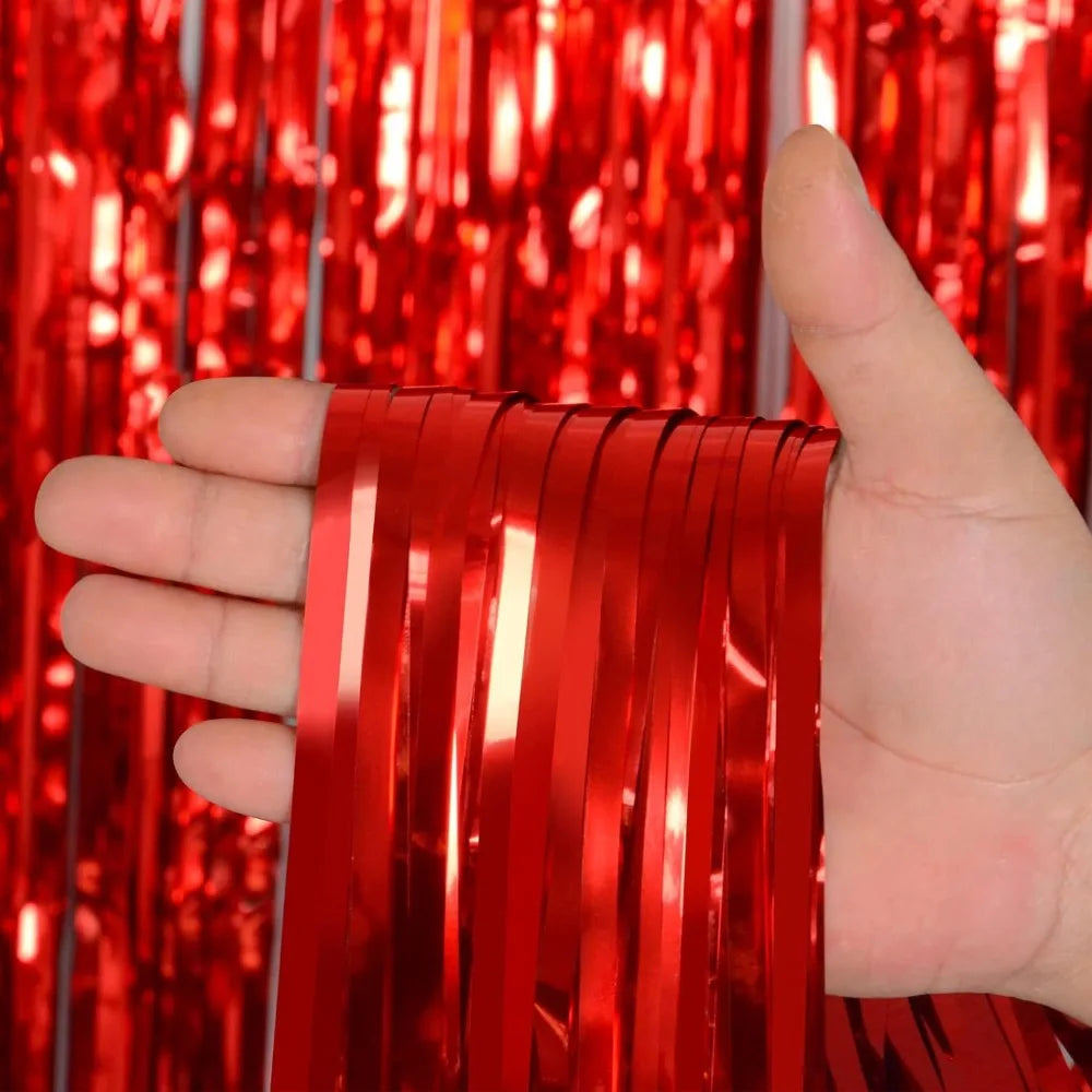 Une main tient une pile de rideaux à franges rouges arc-en-ciel brillants sur un fond rouge vif.