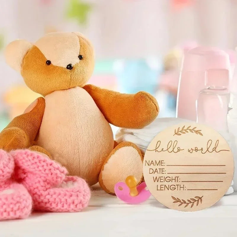 A soft orange and beige stuffed animal next to a round wooden baby name announcement sign.