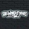 A glowing neon sign on a dark brick wall reads The World Is Yours