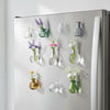 A collection of small glass flower vases and decorative items are displayed on the door of a refrigerator.