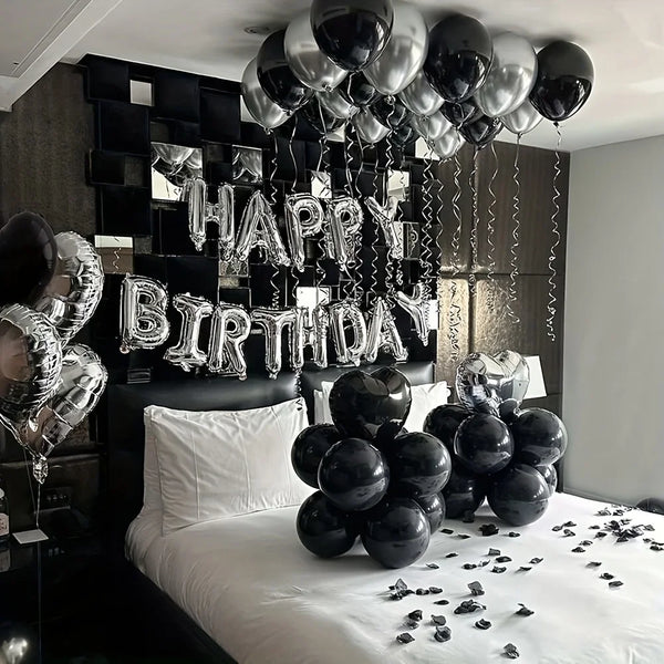 A display of silver and black balloons spelling out Happy Birthday and a heart for party decorations