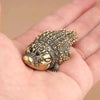 A small, textured copper alligator desk decor is held in a person's hand.