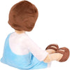 A plush doll dressed in a blue apron and white shirt with brown shoes.