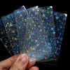 A hand holds several holographic card sleeves with blue and gold star patterns.
