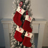 Red knitted socks with letters spell LOVE hanging on a white Christmas tree