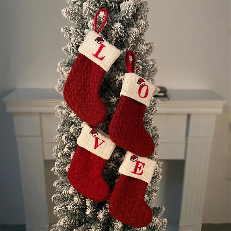 Red knitted socks with letters spell LOVE hanging on a white Christmas tree