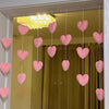 A display of heart-shaped pink string curtains hanging in a doorway.