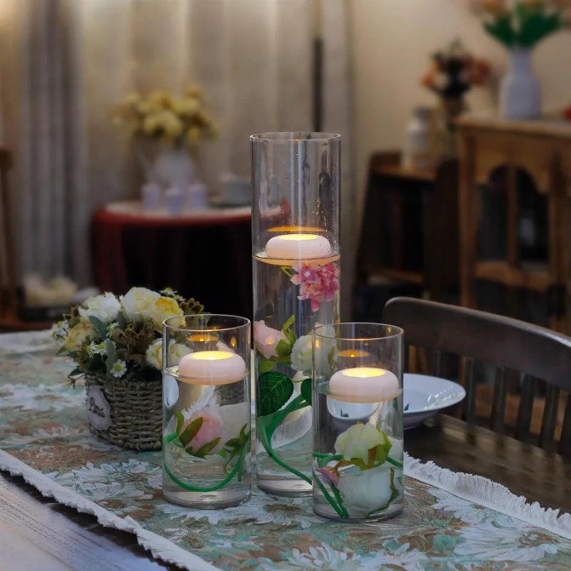 A glass vase holds pink and white flowers next to a wooden cabinet with a dark red cloth.