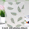 A white album cover featuring a repeating pattern of green leaves on a light background.