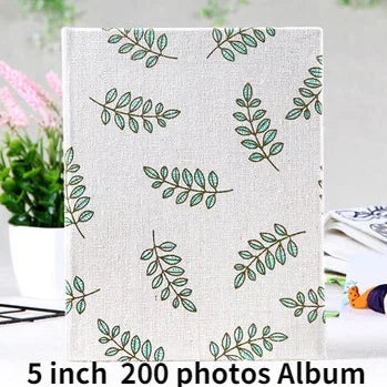 A white album cover featuring a repeating pattern of green leaves on a light background.
