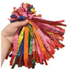 A hand holds a bundle of colorful latex rocket balloons with pink, orange, yellow, and green streamers.