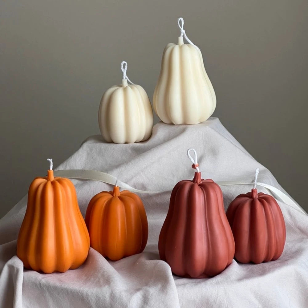 A grouping of four pale yellow and orange silicone pumpkin molds displayed on a white cloth.