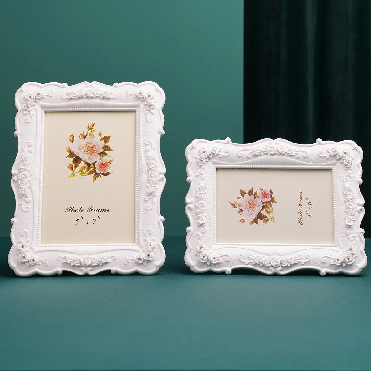 A white ornate photo frame with a floral design is displayed against a teal background.